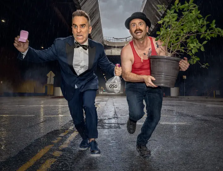 Ben and Arnie running through the rain with a ring box and a very large plant.