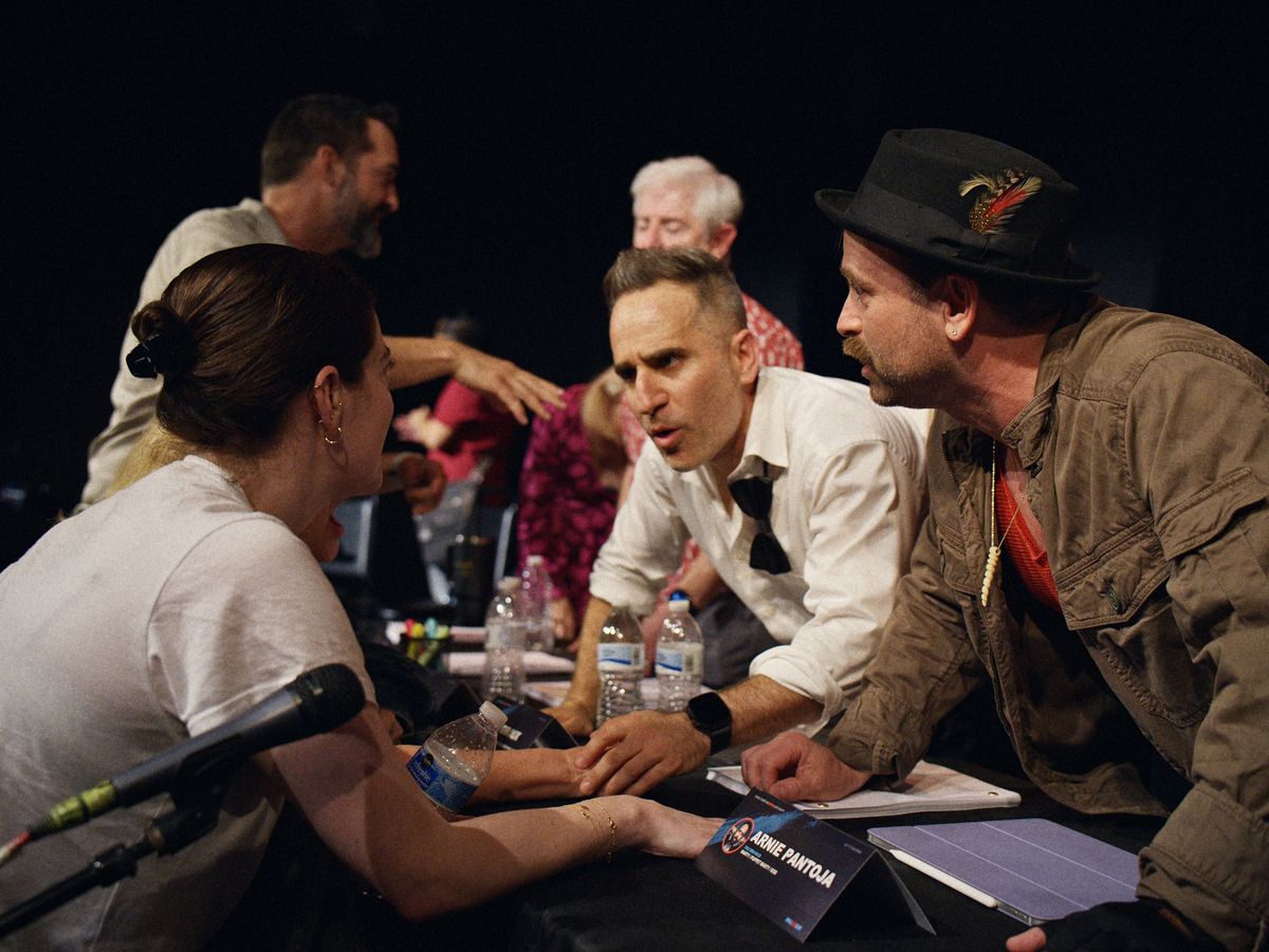 Ben Giroux and Arnie Pantoja huddling with castmates at the table read